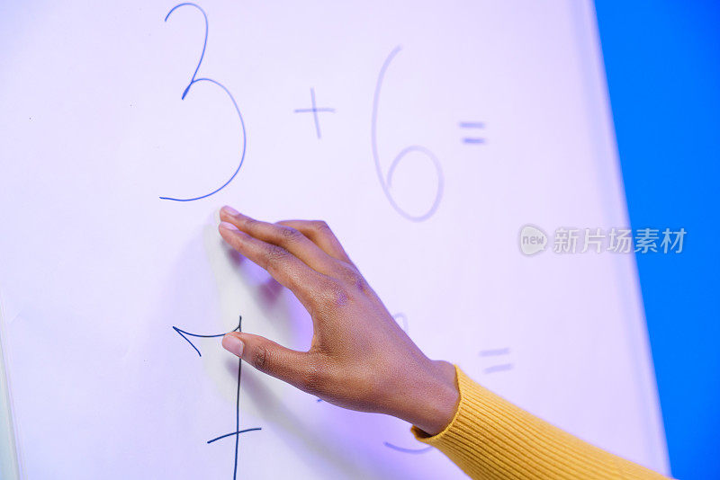 一位年轻教师的手在白板上展示着算术题