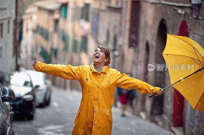 一个穿着黄色雨衣、打着雨伞的小女孩在城市里散步，看到雨点落在她身上，她很兴奋。走,雨,城市