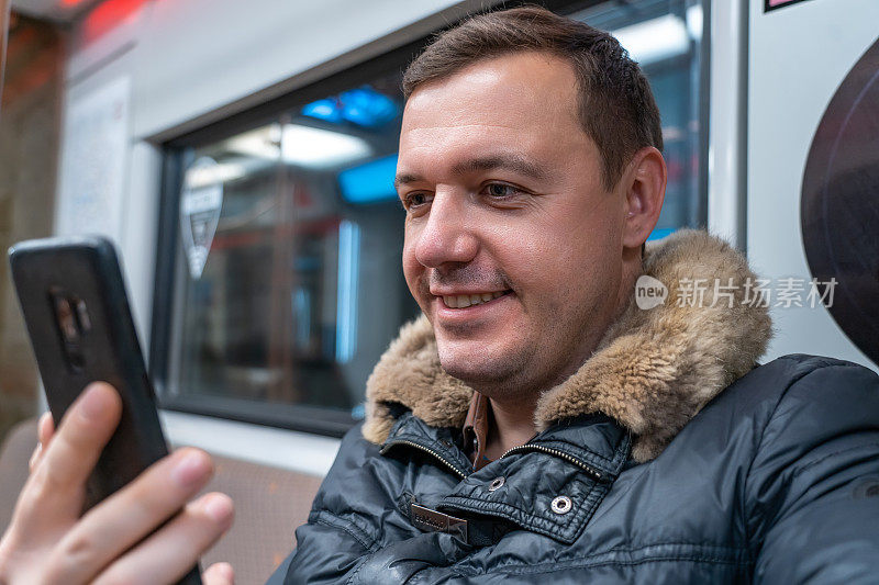 千禧一代积极的家伙看社交媒体的简介肖像，在乘火车回家的时候用手机发短信