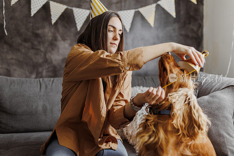 美丽的女人和她的狗狗在家里庆祝她的狗狗生日。