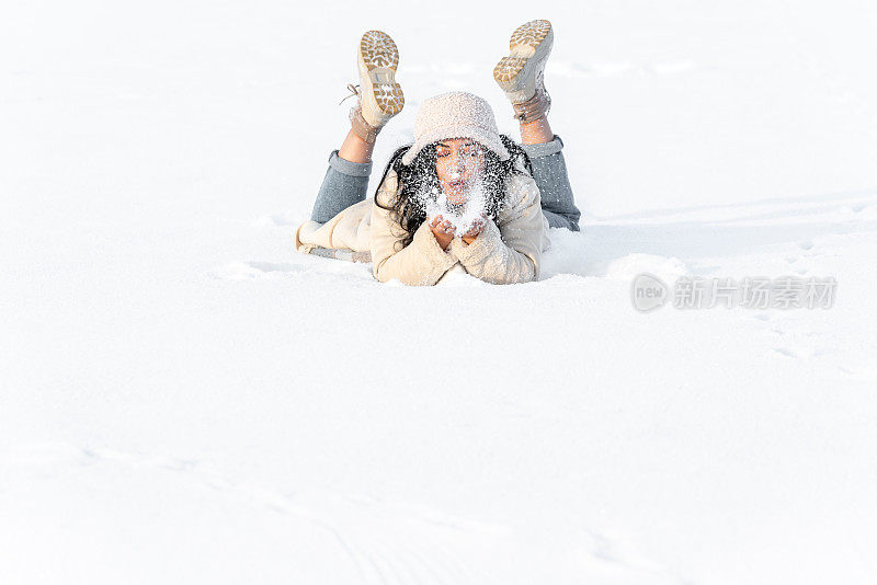 年轻女子在冬天的雪地里玩得很开心