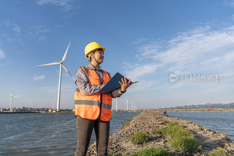 一位亚洲风力发电工程师在海边检查风力发电数据