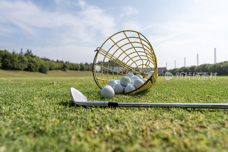 高尔夫球棒:高尔夫球场草坪上的高尔夫球棒和一篮高尔夫球