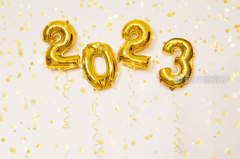 白色背景的金色2022气球上有五彩纸屑和彩灯。新年庆祝概念