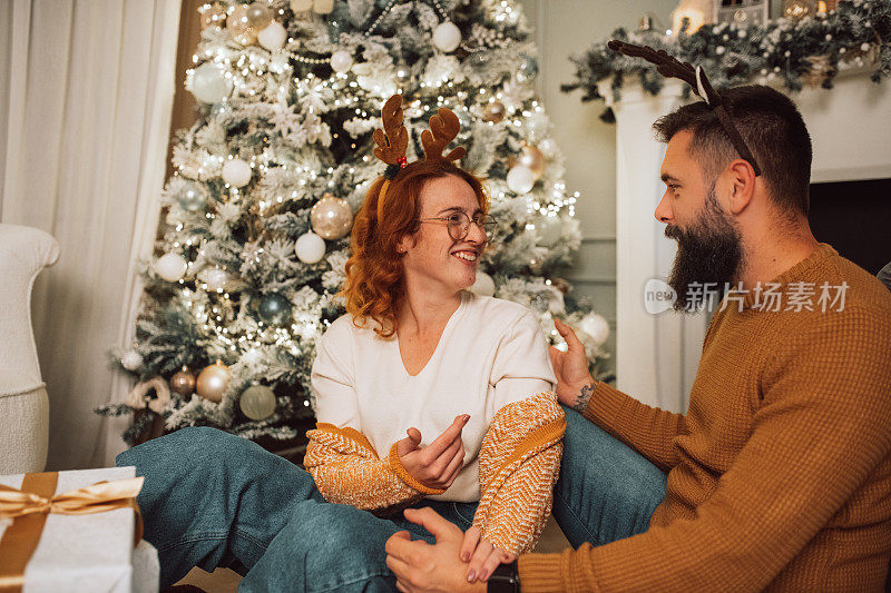 一对夫妇坐在他们装饰可爱的圣诞树前