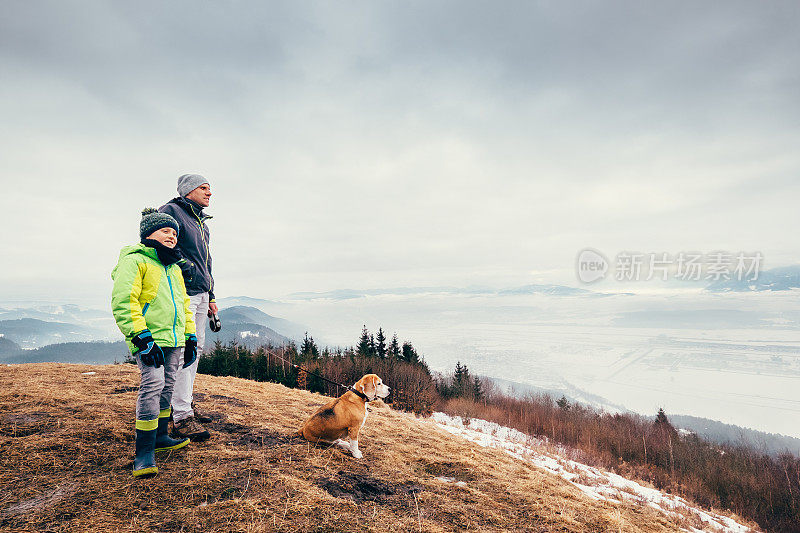 早春时节，父亲带着儿子带着狗在山上散步