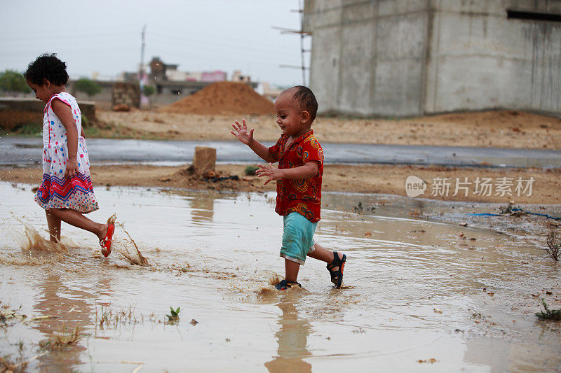 孩子们玩自由雨水水坑溅