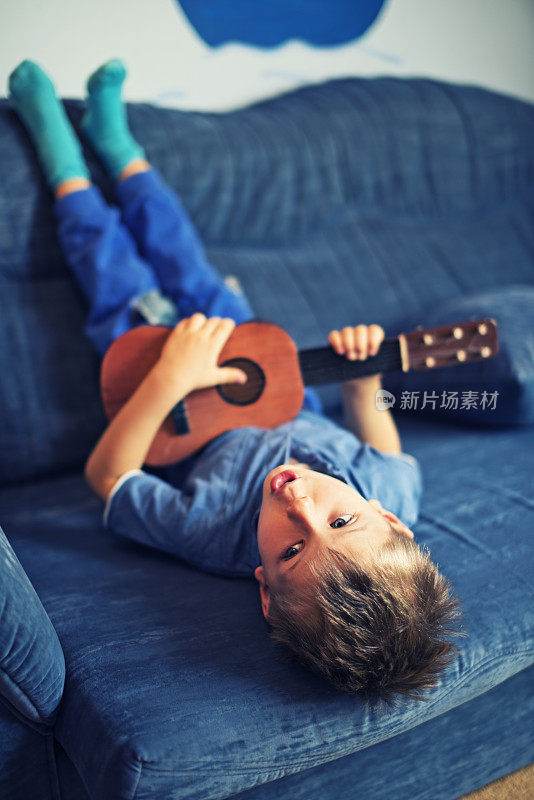小男孩一边弹吉他一边唱歌
