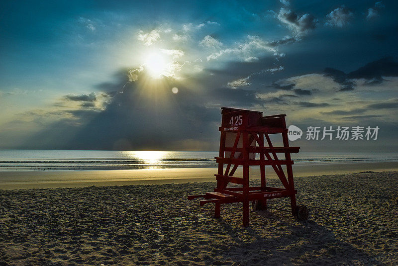 海滩上日出的救生员椅