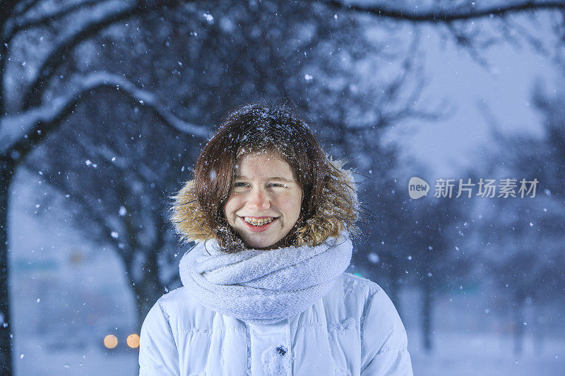 雪下穿着白色夹克的漂亮少女