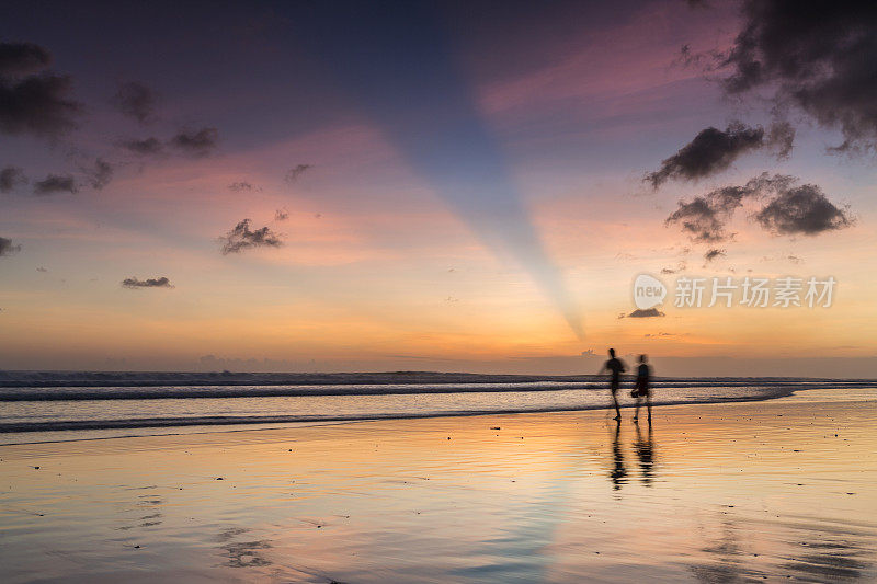 日落时分在海滩上散步的夫妇