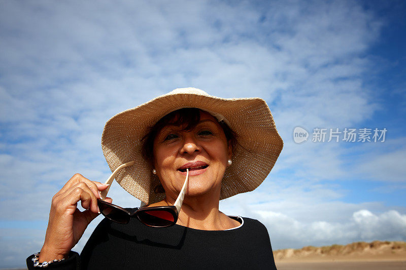 成熟微笑的西班牙妇女太阳镜和太阳帽