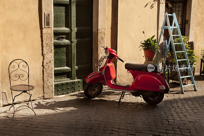 意大利阳光明媚的景象，红色滑板车停在家门口