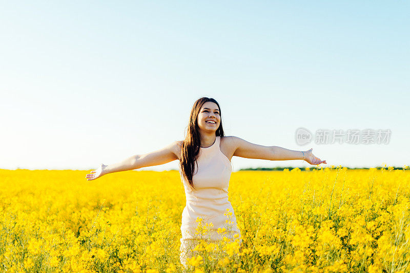 美女在油菜地里享受阳光和夏天