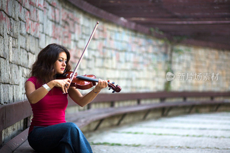 女小提琴家在封闭的砖墙区域演奏