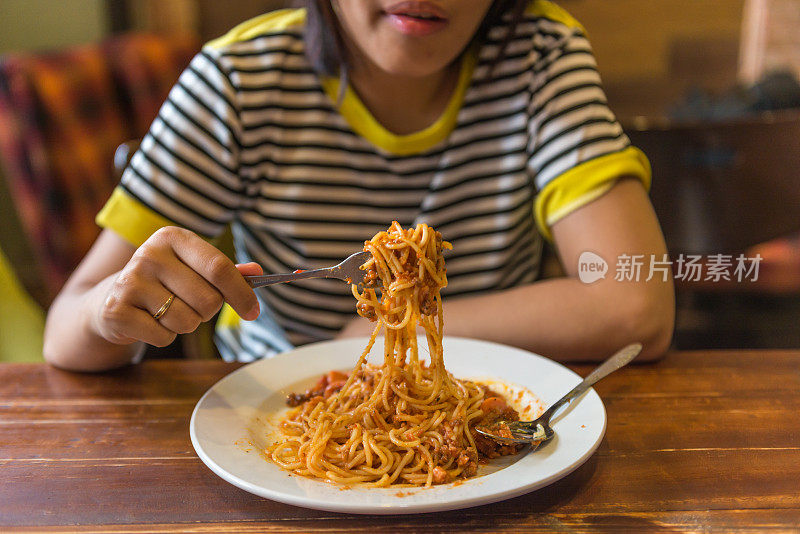 小女孩用叉子和勺子吃意大利面