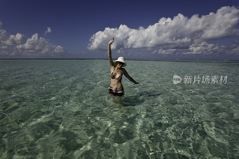 在大开曼群岛，一个女人站在清澈的浅水里