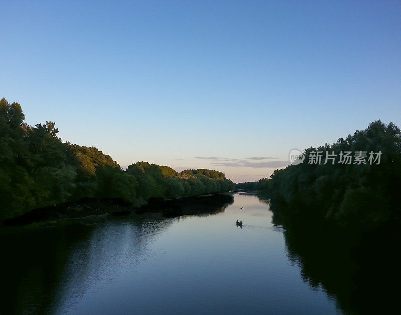 黄昏时分在河边乘船垂钓