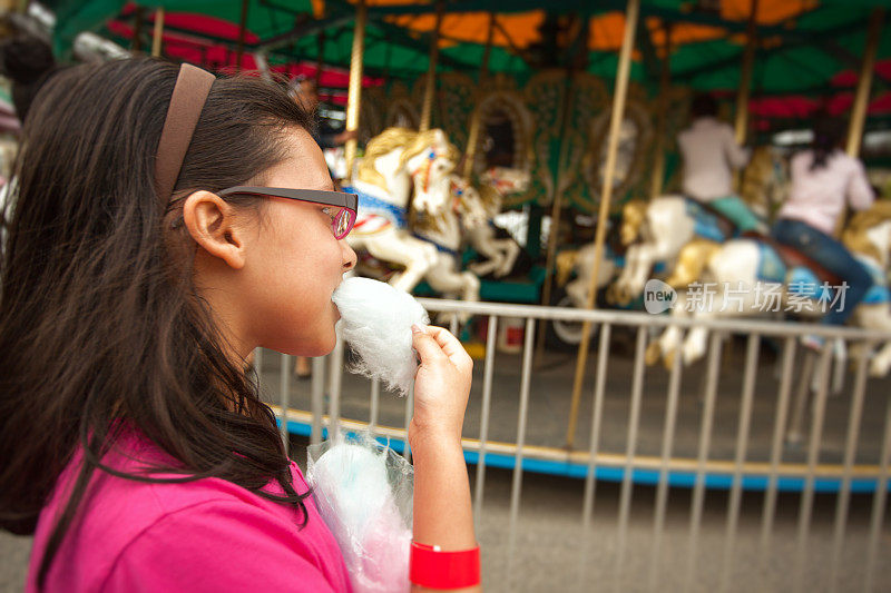 年轻女孩在狂欢节上吃棉花糖