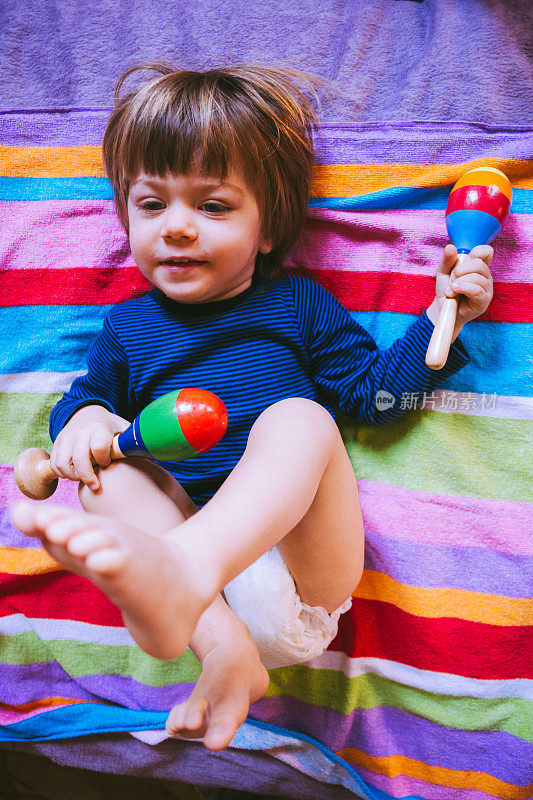 可爱的小男孩在床上玩玩具拨浪鼓