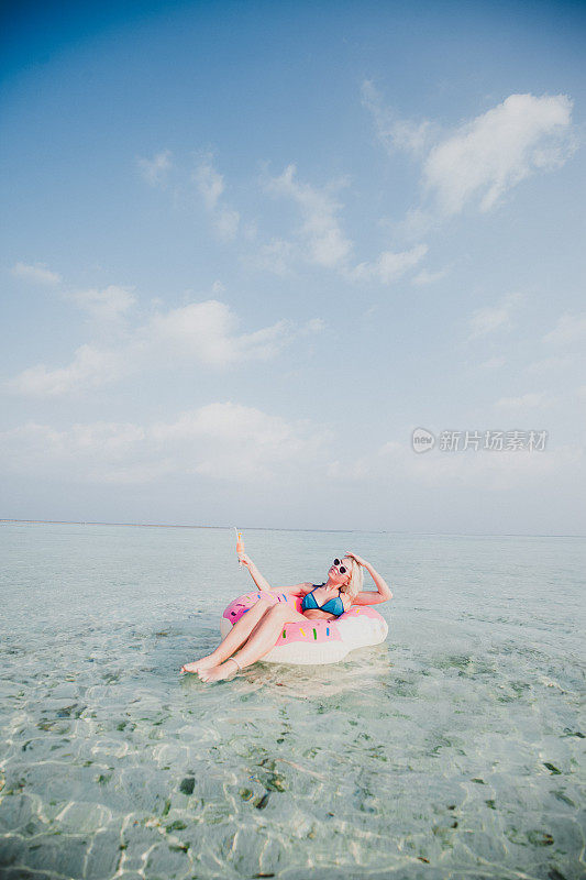 性感的女人浮在水上，有鸡尾酒时间在海洋，马尔代夫