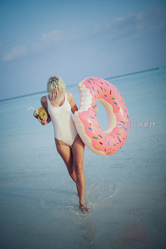 金发女子享受和放松与椰子水在马尔代夫