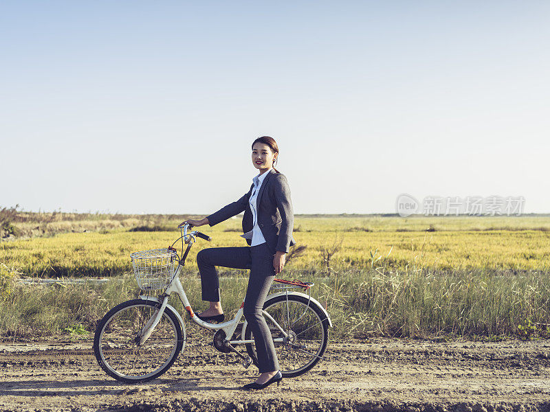 一个年轻的女商人坐在乡下的bicyale上的肖像