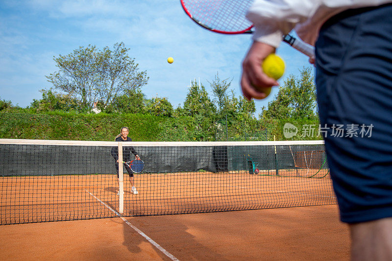 女子在红土场上练习网球