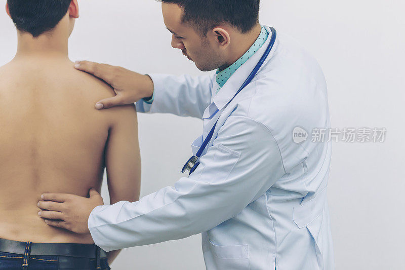 医生在医院用听诊器触摸背部钢板，以确定背部疼痛的原因。体检的概念，医疗保健。