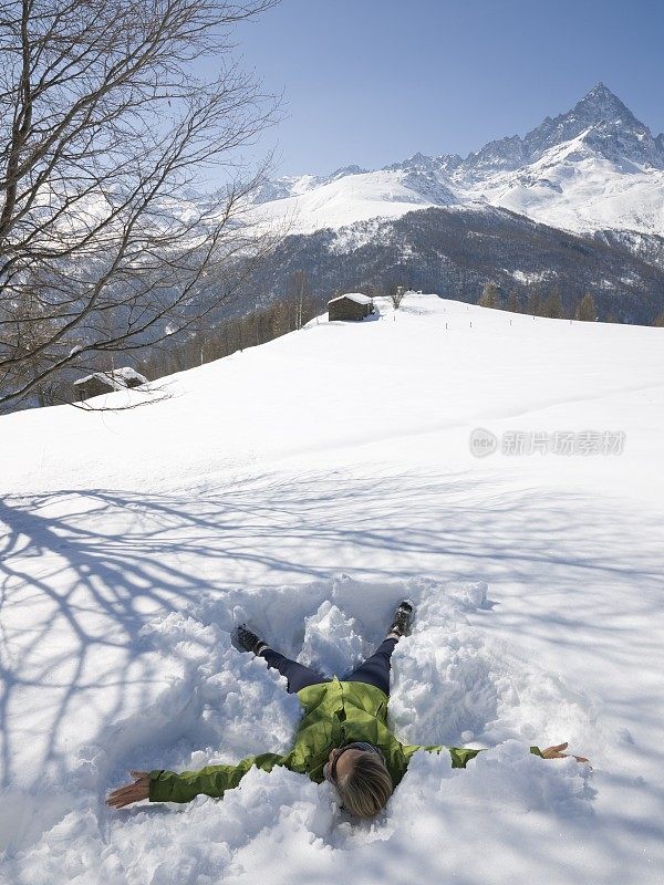 意大利皮埃蒙特，一名女子在山脚下做雪天使