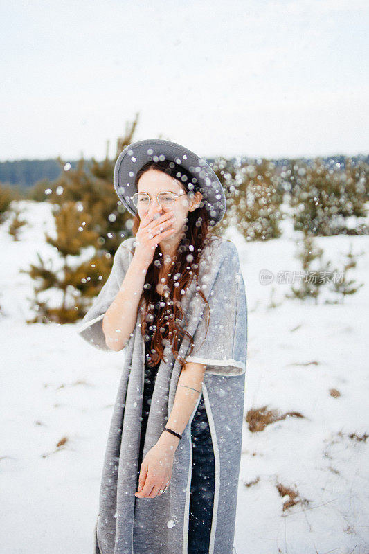 快乐的女人在田野里享受飘落的雪