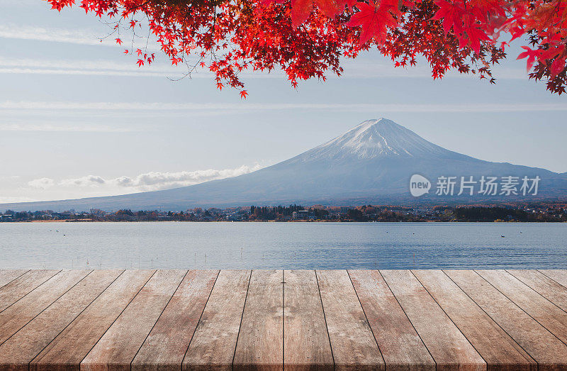 木质桌面在早晨富士山与秋天的红色枫叶的背景-可以用来展示或蒙太奇您的产品。