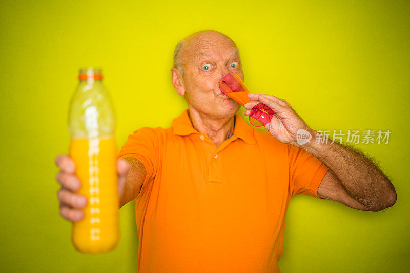 色彩潮时尚的老年人，滑稽的看着老年人喝健康的橙汁