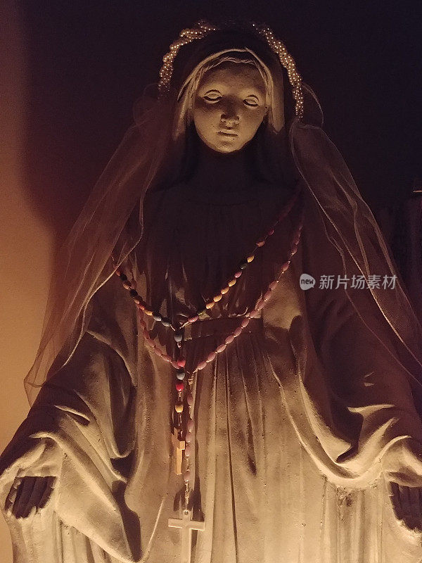 蜡烛点燃圣母雕像戴面纱和念珠