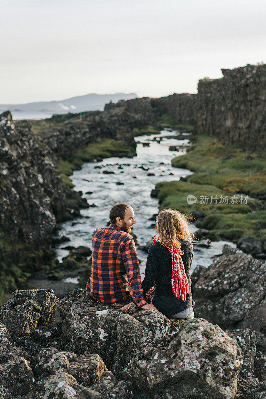 一对夫妇在Öxarárfoss山上的瀑布附近散步