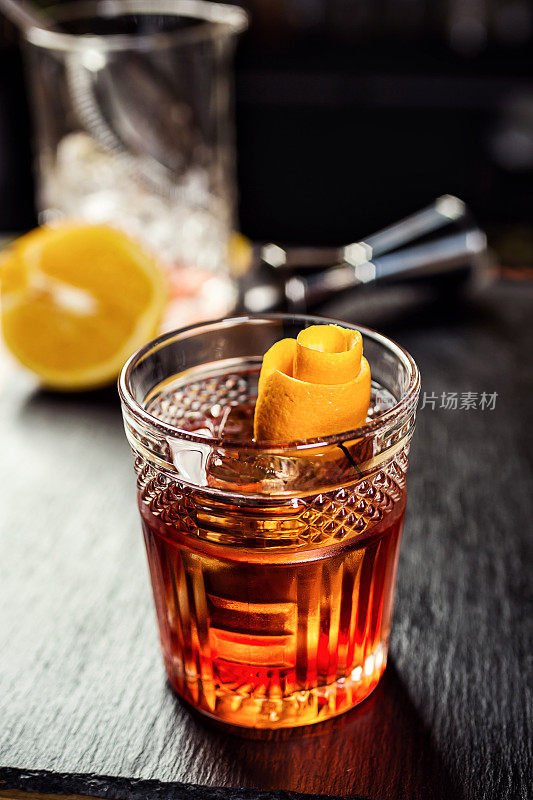 一杯加柠檬和冰块的威士忌(白兰地或白兰地)放在吧台上，背景是一个瓶子