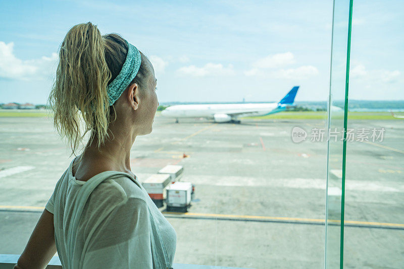 一个年轻女子在机场透过窗户向外看