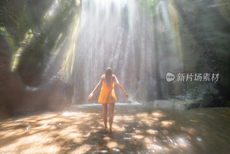 在巴厘岛的热带雨林中，旅行的年轻女子张开双臂拥抱大自然的美丽。人们以自然为旅游理念。