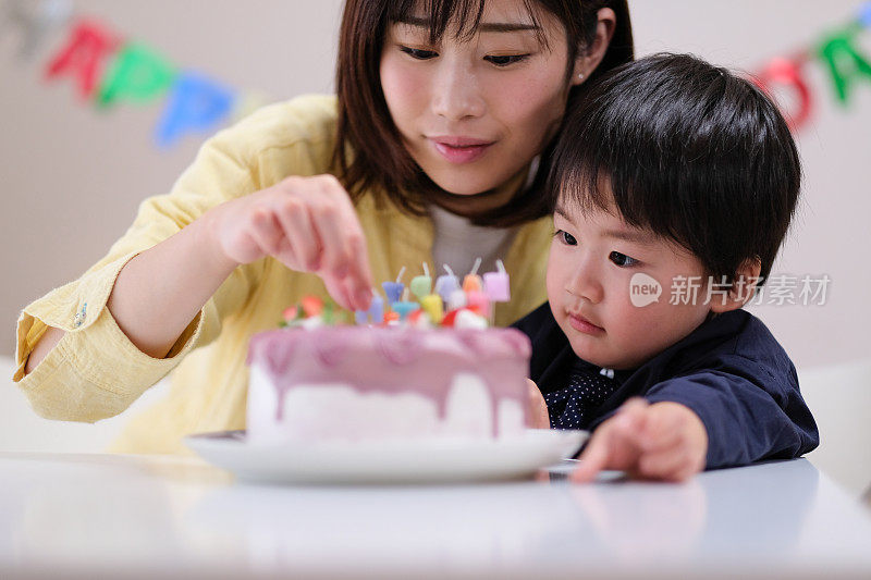 母亲把蜡烛插在儿子的生日蛋糕上