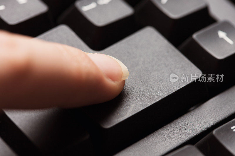 女性的食指轻敲电脑键盘的回车键
