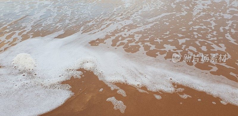 泡沫状的白色海浪拍打着海滩