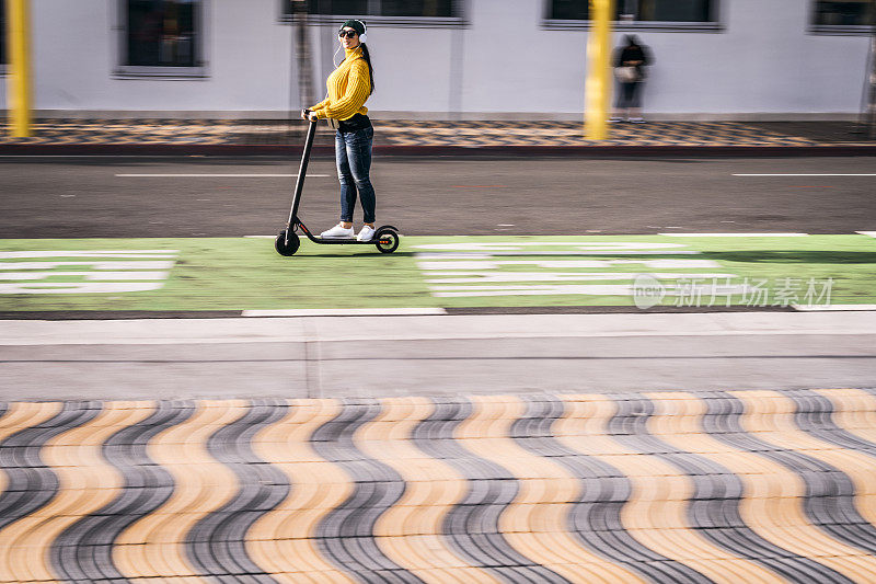 现代女性使用电动踏板车在市区的踏板车和自行车道通勤