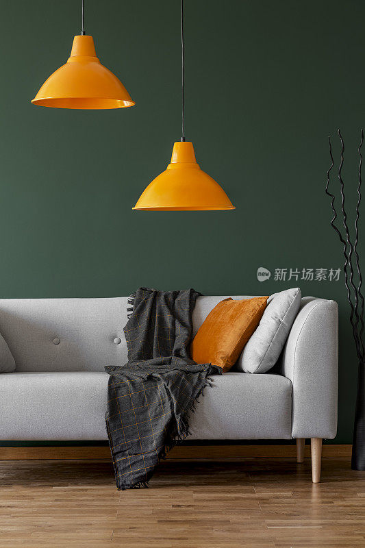 在一个简单的客厅内部，绿色的墙壁上挂着橙色的灯和沙发