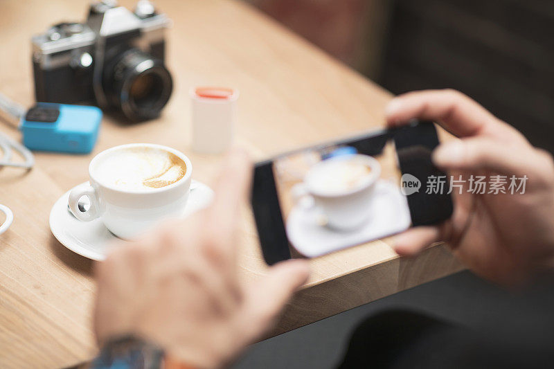 留胡子的帅哥用智能手机拍摄咖啡杯，在咖啡馆餐厅的咖啡休息时间