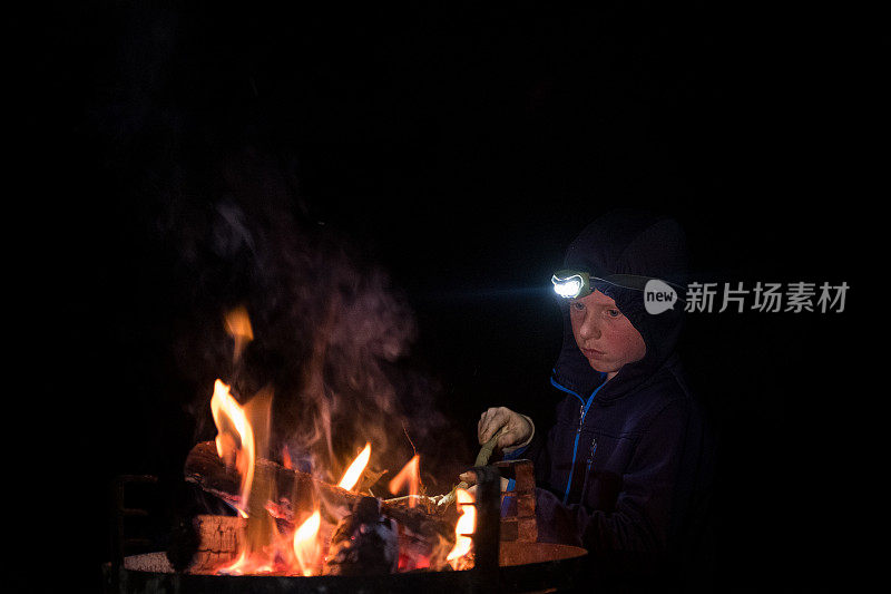 这个小男孩喜欢在营火旁玩