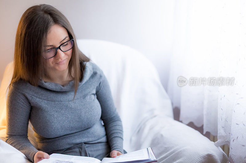 一个年轻女子正在沙发上看书