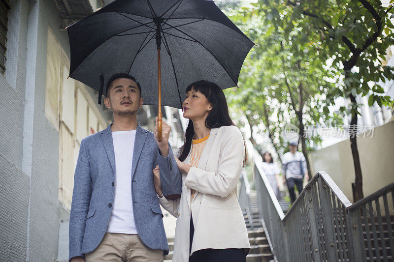 年轻的亚洲夫妇撑着雨伞漫步香港