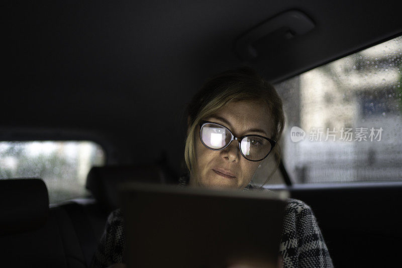 在出租车里工作的女人，用着平板电脑