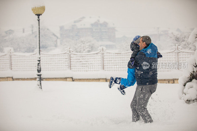 父亲和小儿子正在享受下雪的冬日