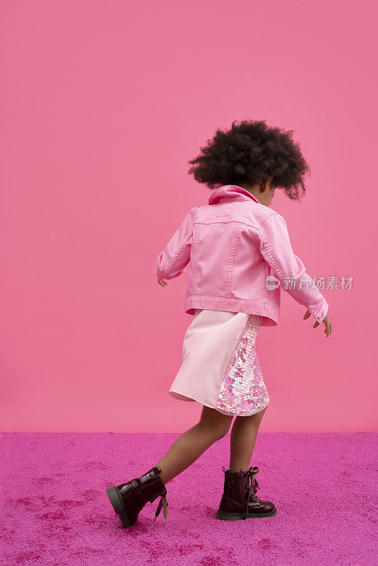 一个非洲裔美国女孩在粉红色的背景上跳舞